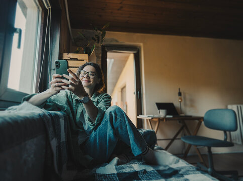 Young woman in green shirt and glasses looking at phone in countryside home office
