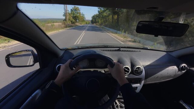 Driving car POV interior view of hands on steering wheel along highway