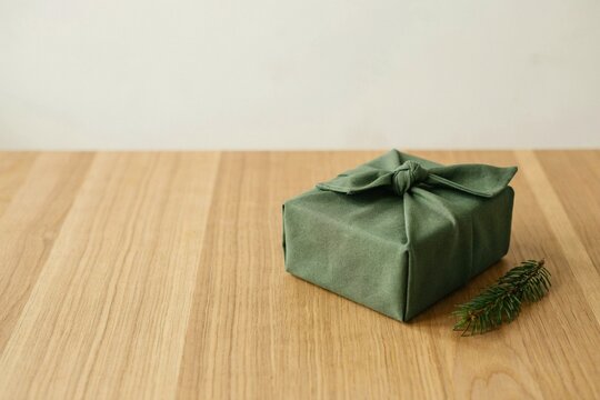 Gift wrapped in green fabric beside a fir sprig