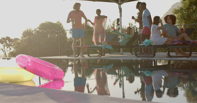 Happy diverse group of friends dancing by swimming pool