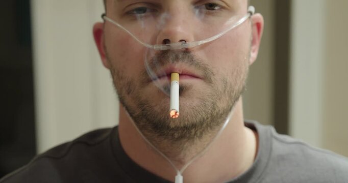 A man wears nasal oxygen tubing while smoking a cigarette in a dramatized scene about unhealthy habits