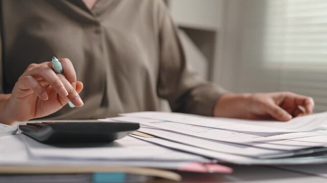 Accounting and finance work, female accountant reading and checking financial documents, reviewing paperwork, tapping paper thoughtfully and using calculator at office desk for audit, bookkeeping and 