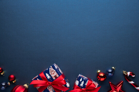 Merry Christmas and Happy Holidays greeting card, frame, banner. New Year. Red Christmas ornaments and gifts, presents on blue background top view. Xmas holiday festive theme. Christmas decoration.
