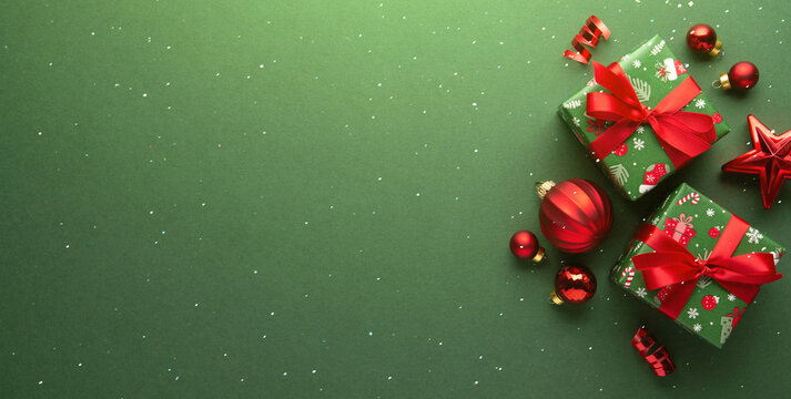 Merry Christmas and Happy Holidays greeting card, frame, banner. New Year. Red Christmas ornaments and gifts, presents on green background top view. Xmas holiday festive theme. Christmas decoration