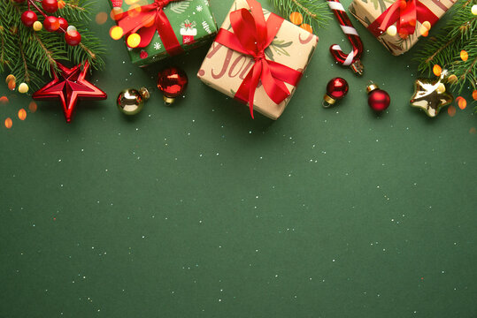 Green Christmas and Happy New Year holiday background with gift boxes, red ribbon bows and festive red ornaments, flat lay with copy space. Greeting card.