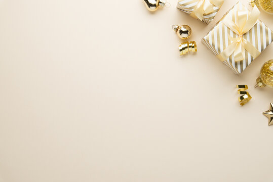 Beige Christmas and Happy New Year holiday background with gift boxes, golden ribbon bows and festive golden ornaments, flat lay with copy space. Greeting card.