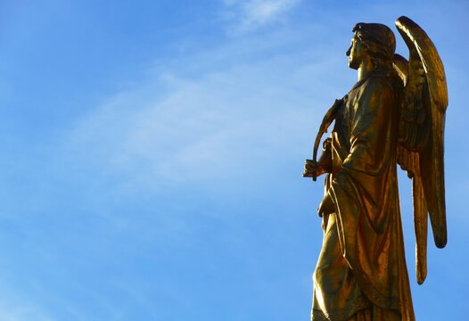 Statue of a golden angel with big wings high in the blue sky near Zagreb Cathedral, statue and architecture background