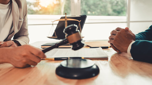 Client signing a legal contract agreement document during consultation with lawyer in office