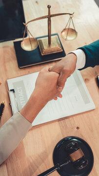 Lawyer and client shaking hands after signing contract agreement in law firm office   