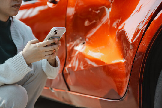 Insurance car agent policy to protect a vehicle is illustrated by a person holding a phone beside a dented car door, connecting insurance with car damage documentation and planning.