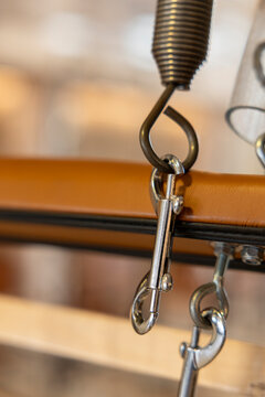 Pilates reformer spring and metal clips connecting to a padded carriage