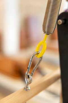 Pilates reformer spring and carabiner attached to wooden frame