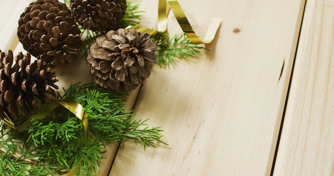 Image of christmas decorations with pine cones and copy space on wooden background
