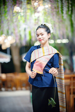 Smiling young Thai woman in traditional Northern Thai dress holding a traditional Thai hanging   toy (Pla Taphiang) outside the Wat Ton Kwen temple, Chiang Mai, Thailand