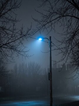 Blue LED streetlight glowing in foggy urban environment  