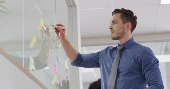 Caucasian businessman using transparent board at office