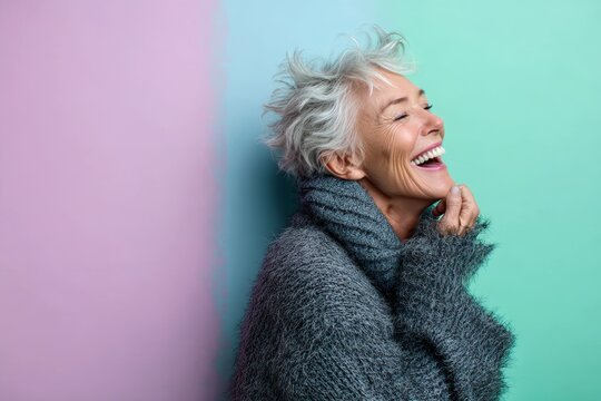 Portrait of a jovial caucasian woman in her 60s laughing over pastel or soft colors background