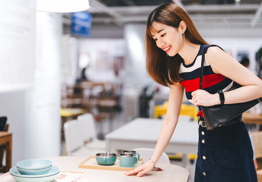 Adult asian woman choosing table product home accessories shopping buying new furniture interior at warehouse showroom