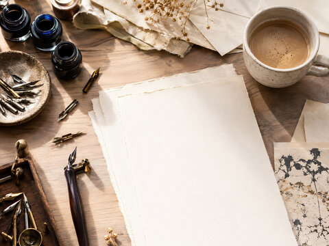 Writing implements on a wooden table. A fountain pen on a blank sheet of paper.