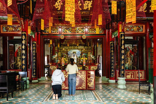 Vietnam. Central region. Quang Nam Province. Hoi An. The Phuoc Kien Pagoda. Two worshippers in prayer before the main altar, which is dedicated to the sea goddess Thian Hau