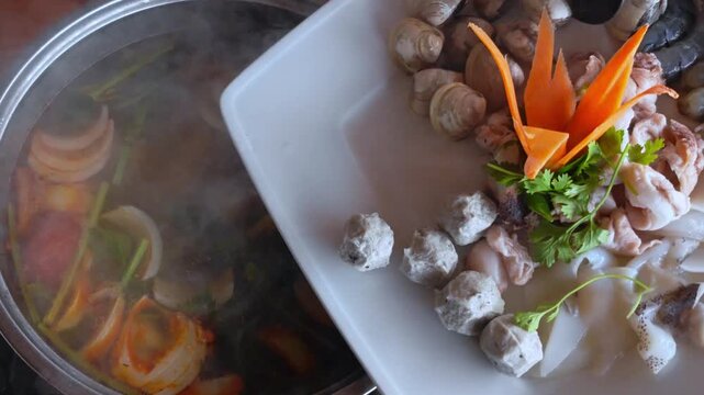 Cooking soup. Seafood and vegetables hot pot served in Asian restaurant. Vietnamese Hot pot cuisine. Steming hot pot over flame at Asian restaurant table.