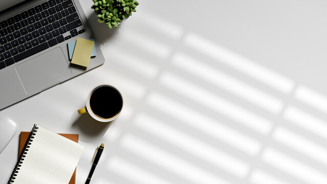 Top View Office Workspace Flat Lay with Laptop, Coffee, Notebook and Plant on White Desk with Window Shadow