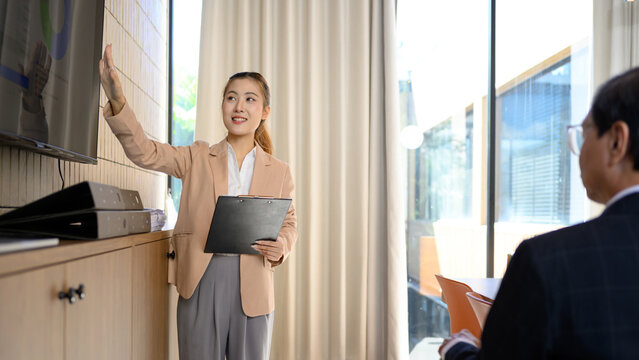 Businesswoman Presenting to Audience Holding Clipboard in Office