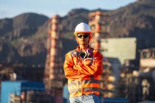 Mining worker standing at a refinery, wearing high-visibility safety gear