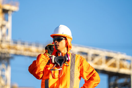 Mining worker in protective gear speaking into a radio at an industrial site