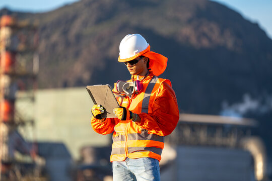 Mining worker checking a tablet at an industrial site, wearing protective gear