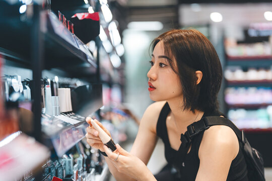 Adult woman shopping for cosmetics in a modern beauty store choosing makeup trend products on a shelf