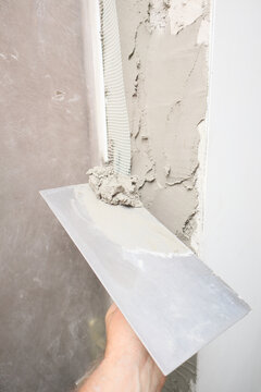 Worker applying plaster to door jamb slope during doorway installation and interior renovation concept