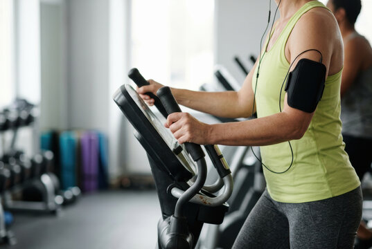Female fitness gym workout exercise treadmill cardio sweat training athlete sport healthy lifestyle earphone music smartphone armband activewear tank indoor focus strength endurance equipment
