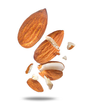 Flying whole and broken almond nuts with pieces falling in motion isolated on a white background