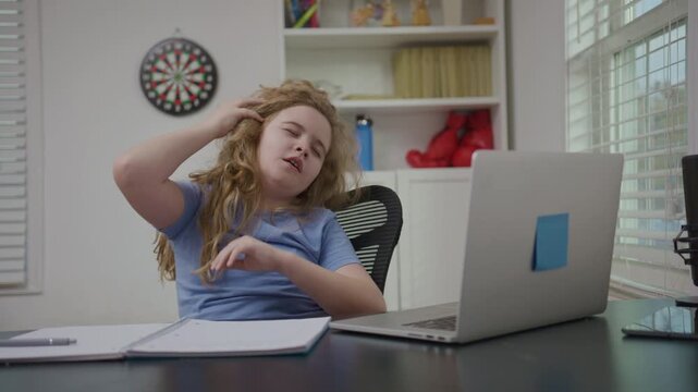 Tired school child bored with online learning. Tired school kid frustrated by school demands. Tired school boy learning remotely at home.