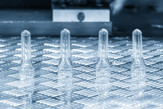 Sample of plastic bottle preforms on an aluminum plate in a light blue tone scene