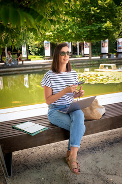 Smiling female freelancer working remotely on a laptop outdoors