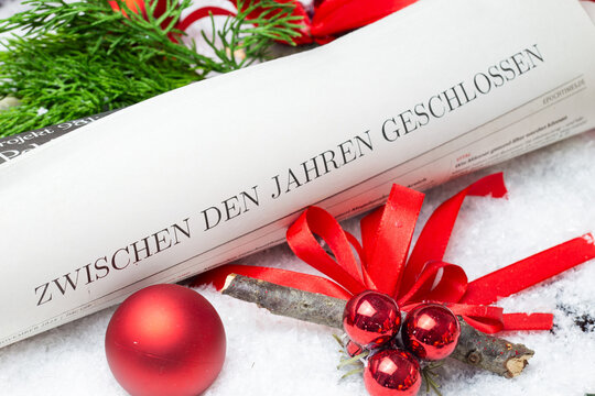 Betriebsferien zur Weihnachtszeit: Zeitung mit Text ZWISCHEN DEN JAHREN GESCHLOSSEN mit weihnachtlicher Dekoration (digital bearbeitet)