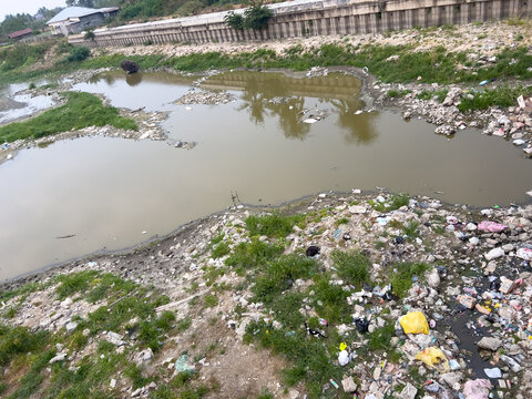 Polluted Riverbank With Plastic Waste and Trash