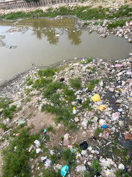 Polluted Riverbank With Plastic Waste and Debris