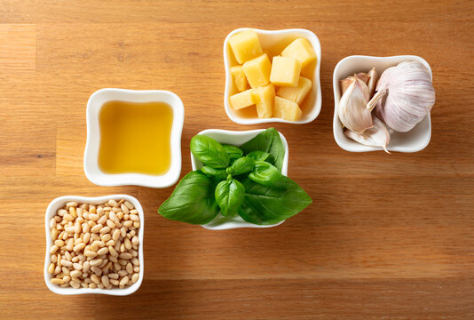 Ingredients for traditional Italian pesto recipe on a wooden background.