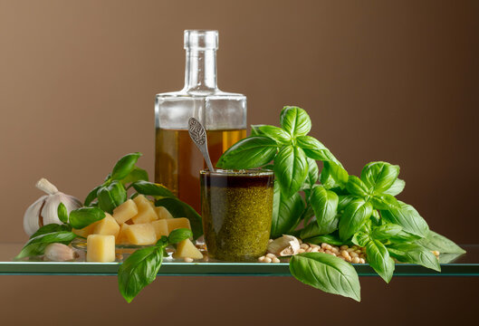 Pesto sauce and ingredients on a glass table.