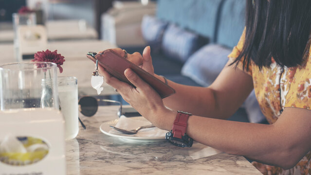 Close-up of Woman hand uses smartphone for mobile communication, during relaxation at restaurant cafe table. Digital lifestyle and internet connection concept