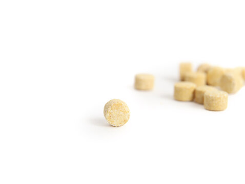 Isolated tea ball with defocused pile in random placing. Yellow lemon tea tablets. Alternative to loose leaf tea. Dissolves in hot and cold water. Selective focus.