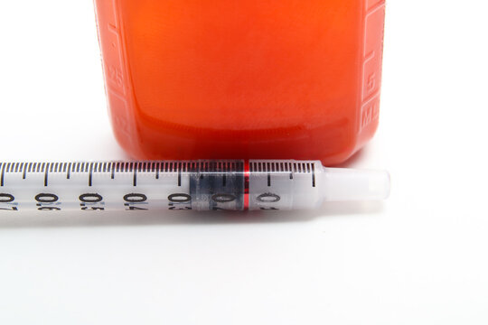Close up of dosing syringe with oral steroid medication bottle. Liquid anti-inflammatory for pets or children, dispensed by owner or parent. Dosage line visible. Selective focus.