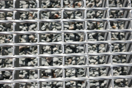 Macro detail of galvanized steel grating floor with crushed stones underneath
