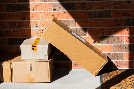 Cardboard boxes piled outside door of house from online home delivery orders