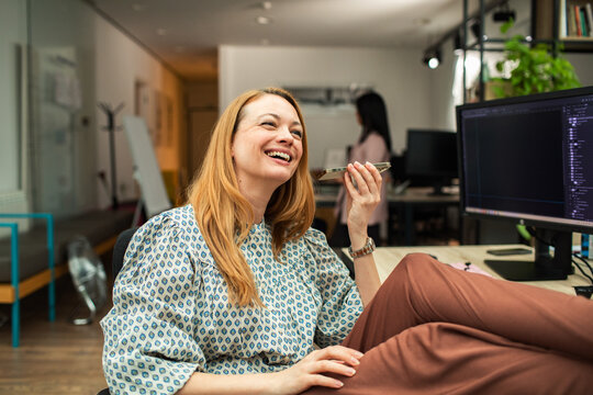 Smiling developer using smartphone voice dictation at desk