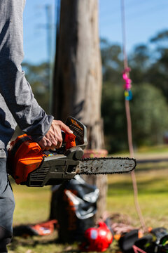 arborist tree surgeon holding a chainsaw by tree ready to begin work