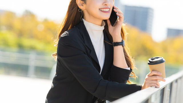 オフィス街でスマートフォンで話す女性・ビジネスウーマン